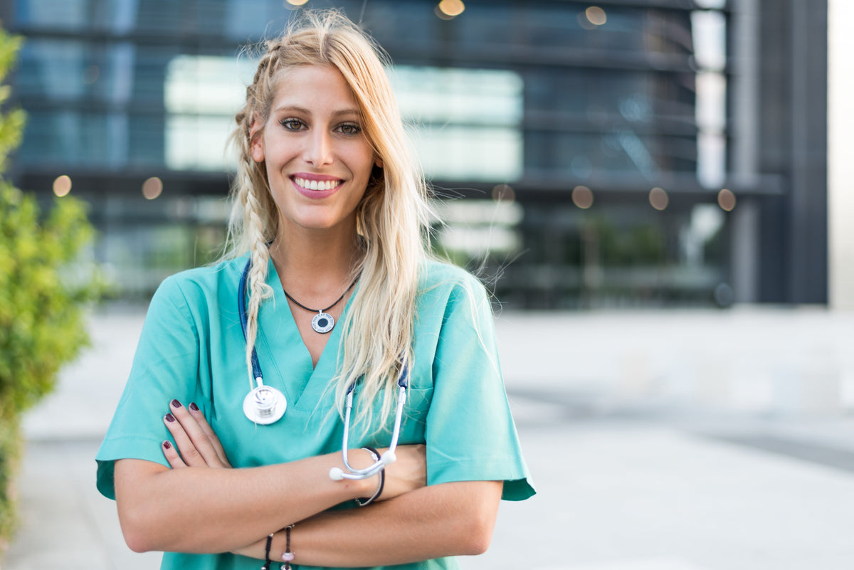 Praticienne souriante en tenue médicale, photographiée en extérieur
